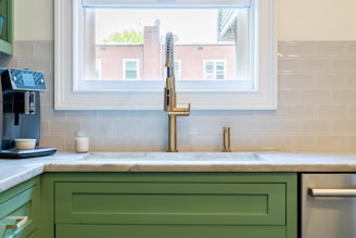 a kitchen with green cabinets and a gold faucet