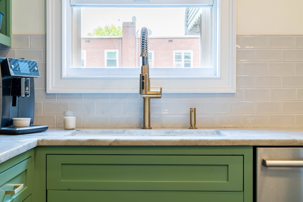 a kitchen with green cabinets and a gold faucet