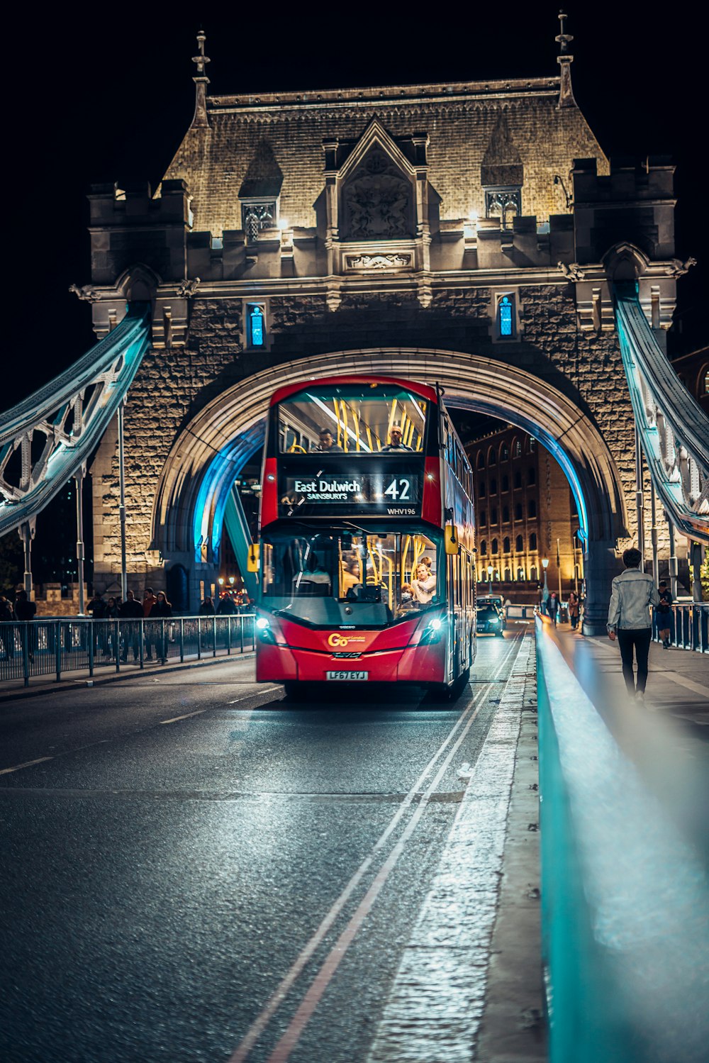 a red double decker bus driving under a bridge