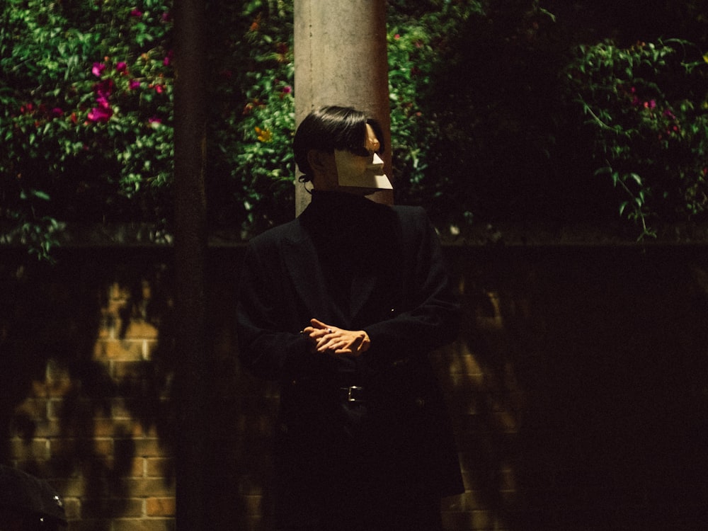 a person with a mask on their face standing next to a tree