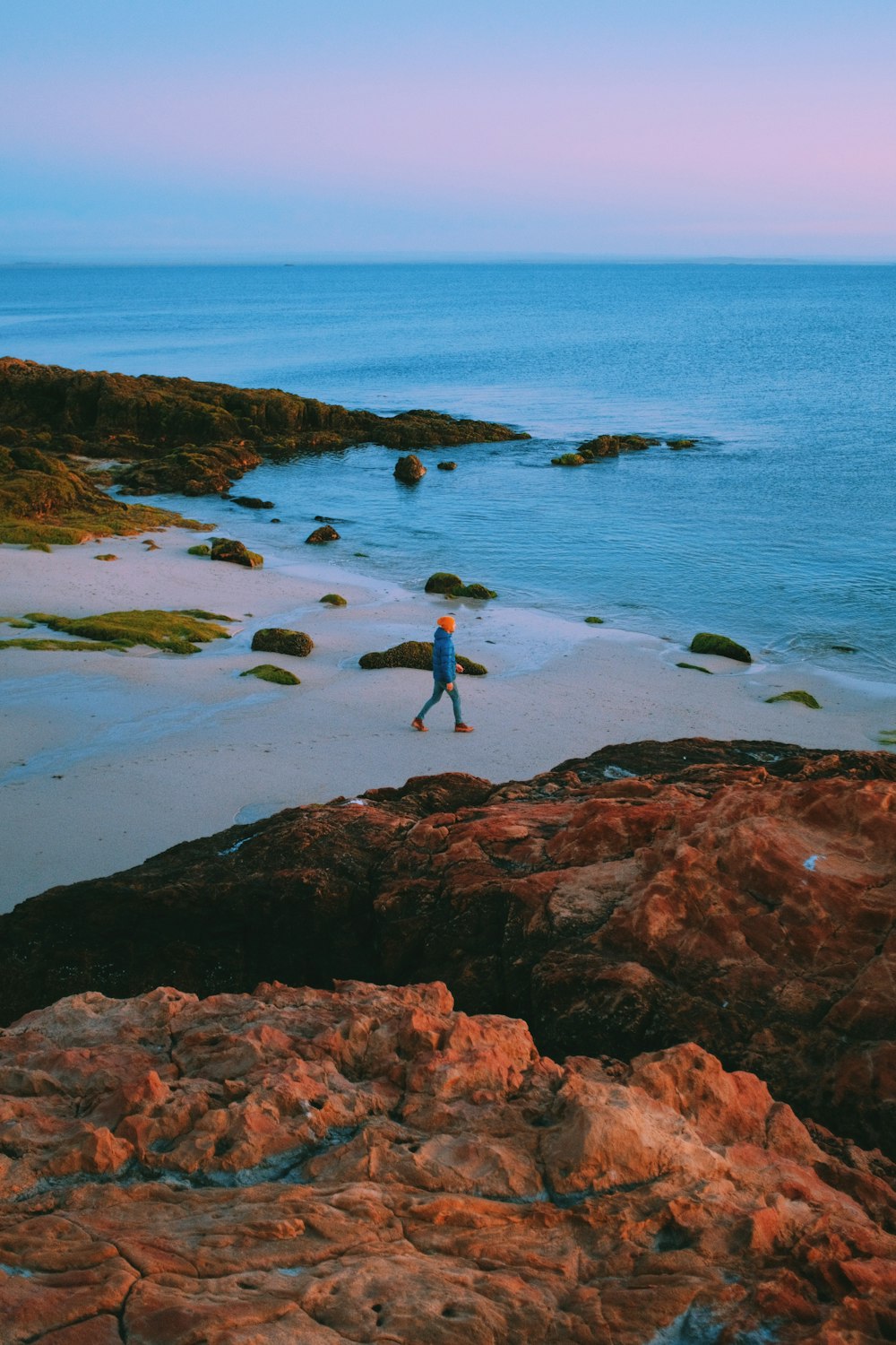 a person walking on a beach next to the ocean