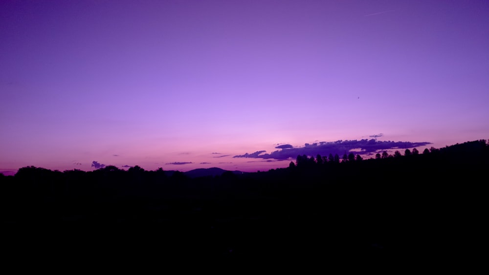 a purple sky with a few clouds in the distance