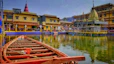 a row boat sitting on top of a lake next to a yellow building