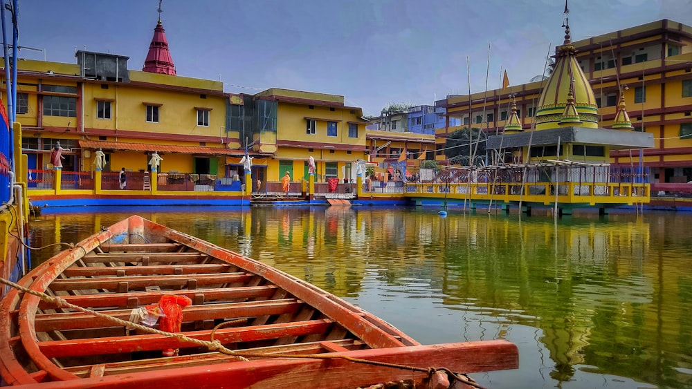 a row boat sitting on top of a lake next to a yellow building