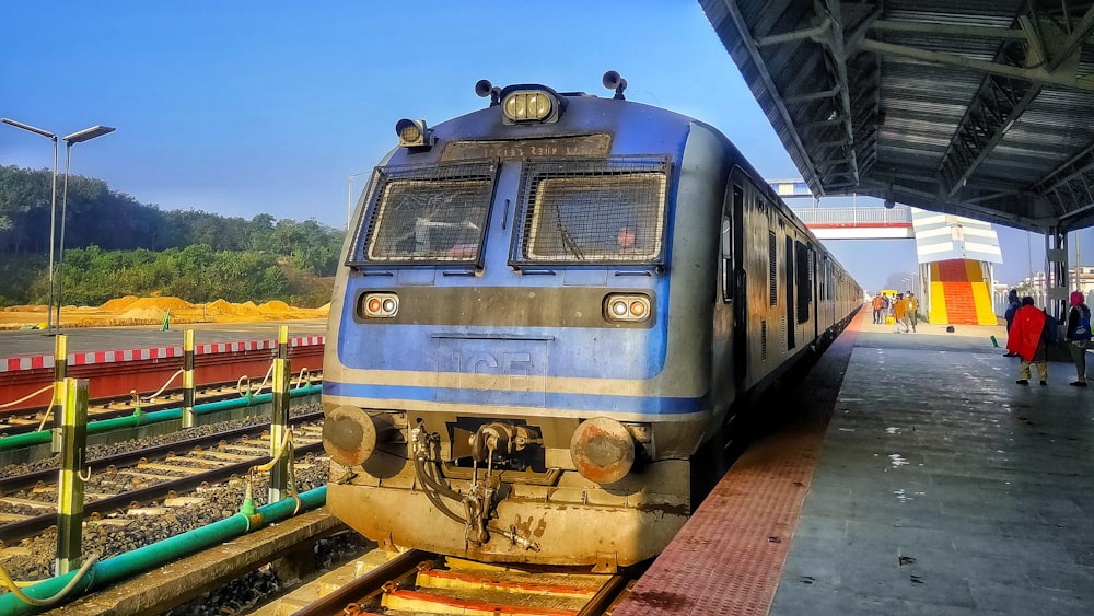 a blue and silver train pulling into a train station