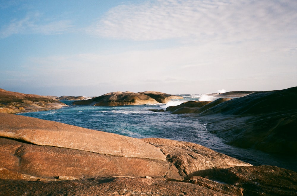 a body of water sitting next to a rocky shore