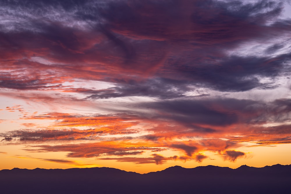 a sunset with clouds and mountains in the background