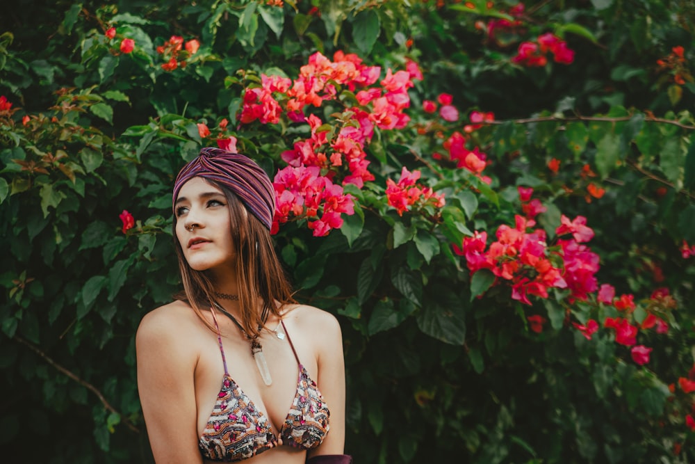 a woman in a bikini standing in front of flowers