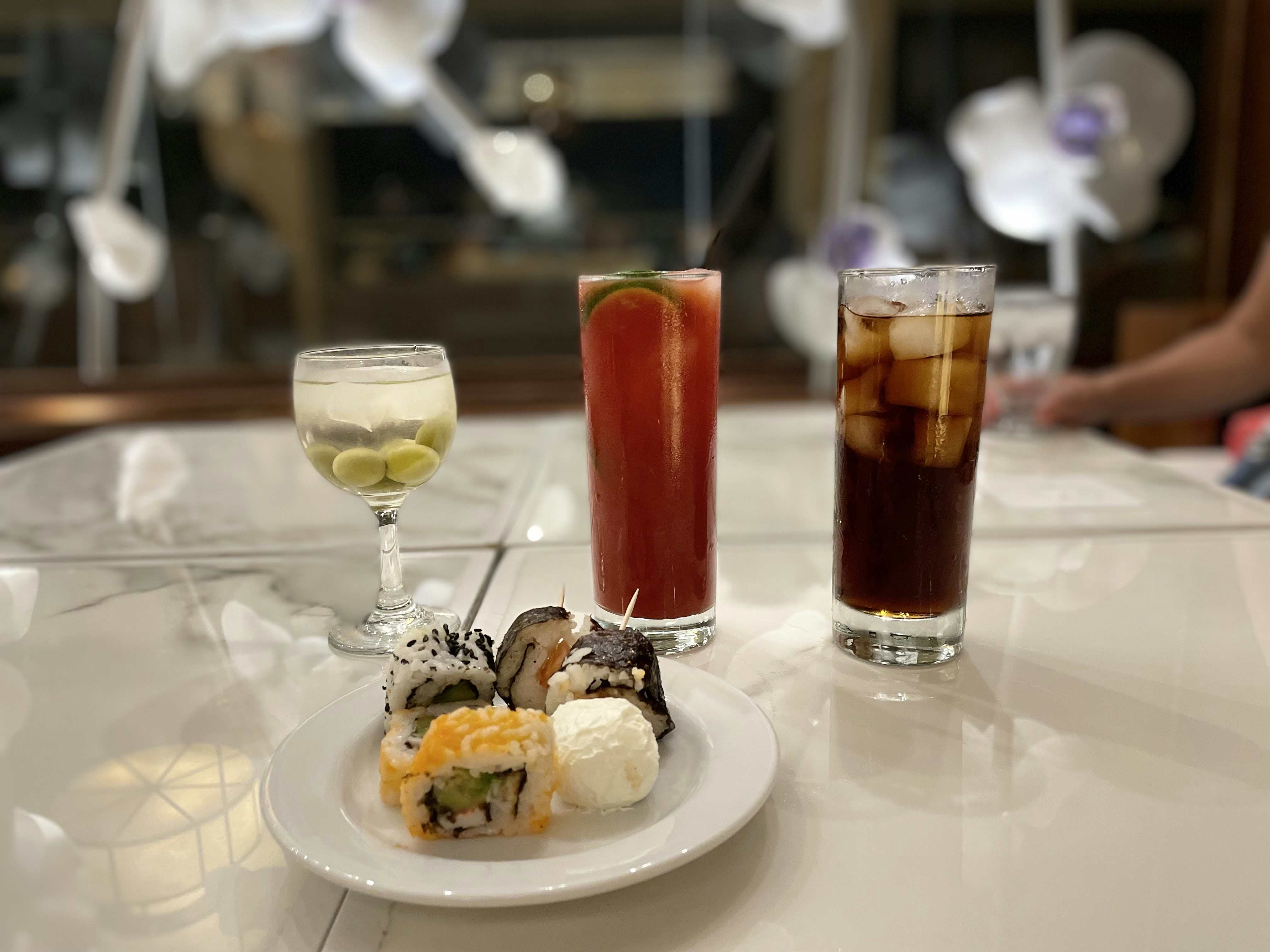 a white plate topped with sushi next to a glass of wine, 