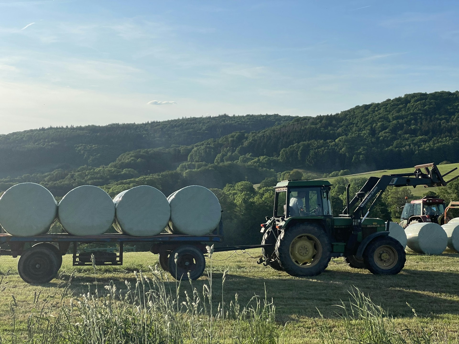 a tractor pulling a trailer full of bales of hay