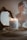 A lit candle labeled 'Emotional Support Candle' sits in a shallow wooden dish. Behind it, a classic-style bust and an ornate, antique mirror add to the aesthetic. The background features soft, neutral tones creating a cozy and serene atmosphere.