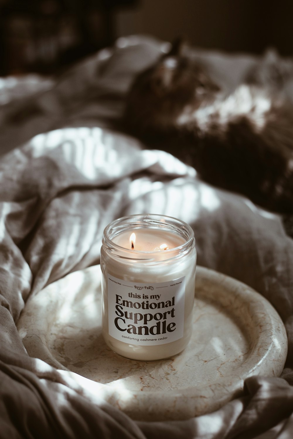 a candle sitting on a plate on a bed