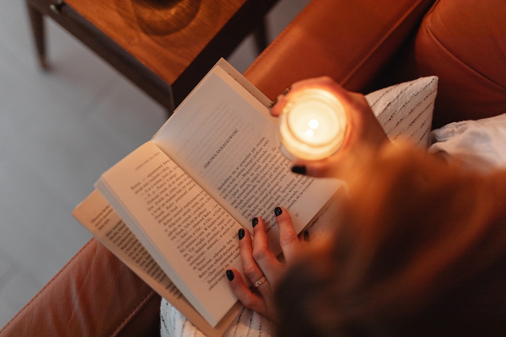 a woman sitting on a couch reading a book