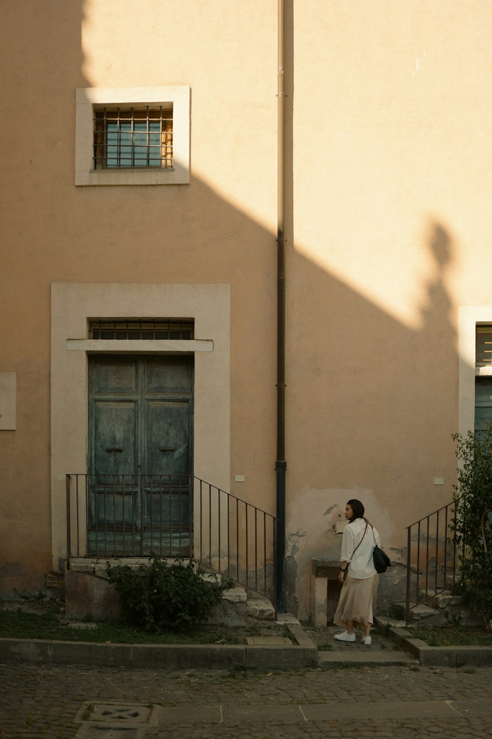 a woman standing in front of a building holding an umbrella