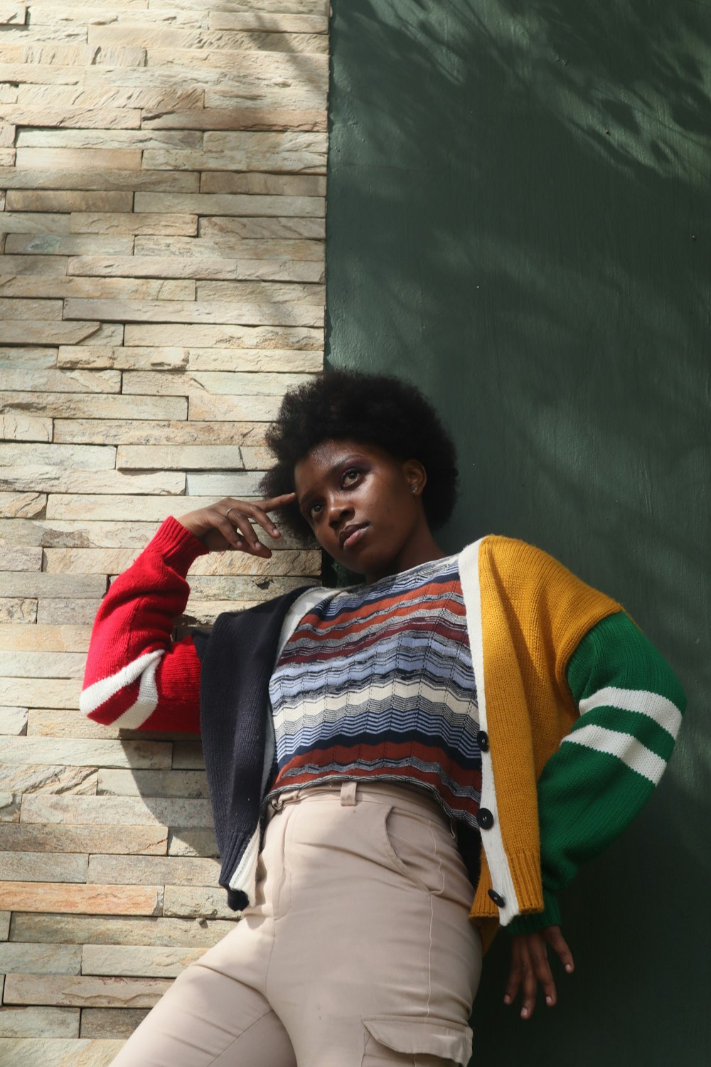 a woman leaning against a brick wall