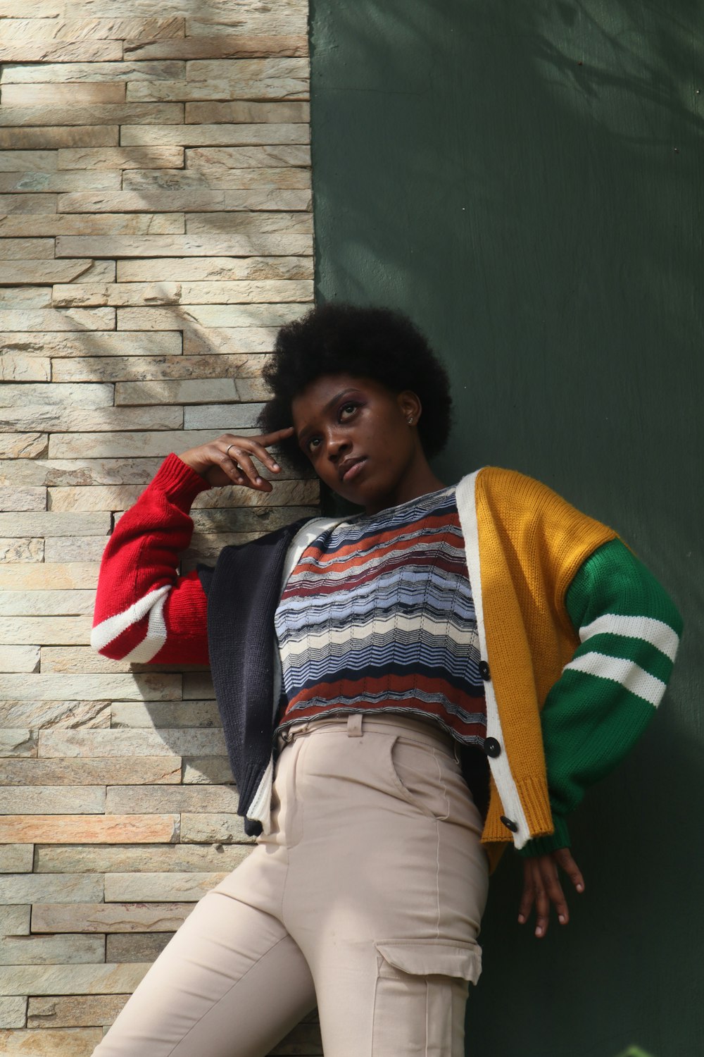 a woman leaning against a brick wall while talking on a cell phone