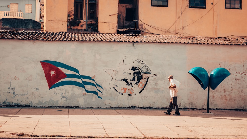 a man walking past a wall with a painting on it