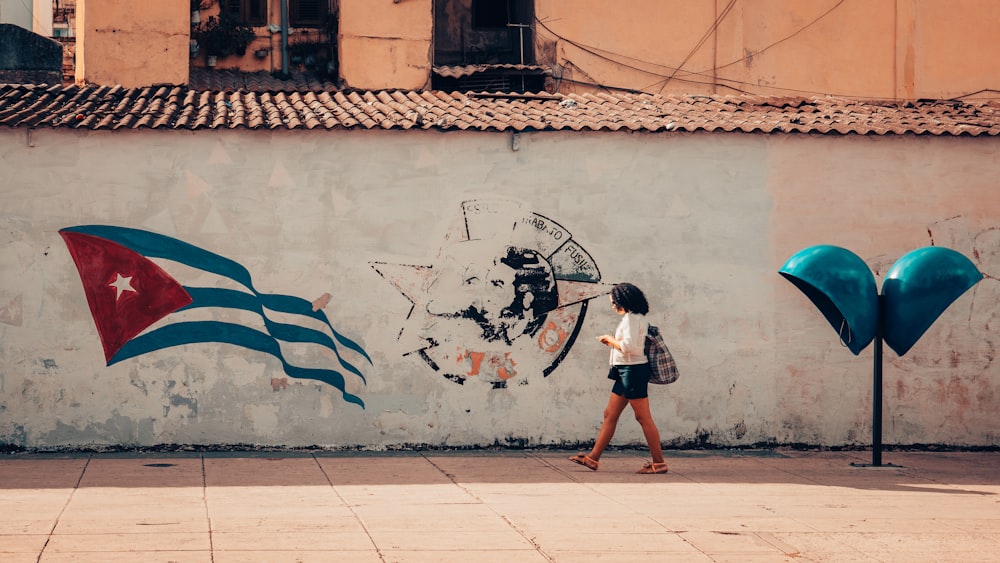 Una mujer caminando más allá de una pared con una bandera pintada en ella