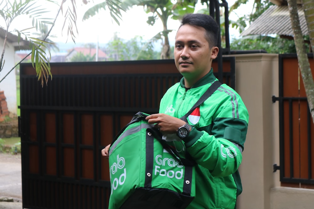a man in a green jacket holding a green bag