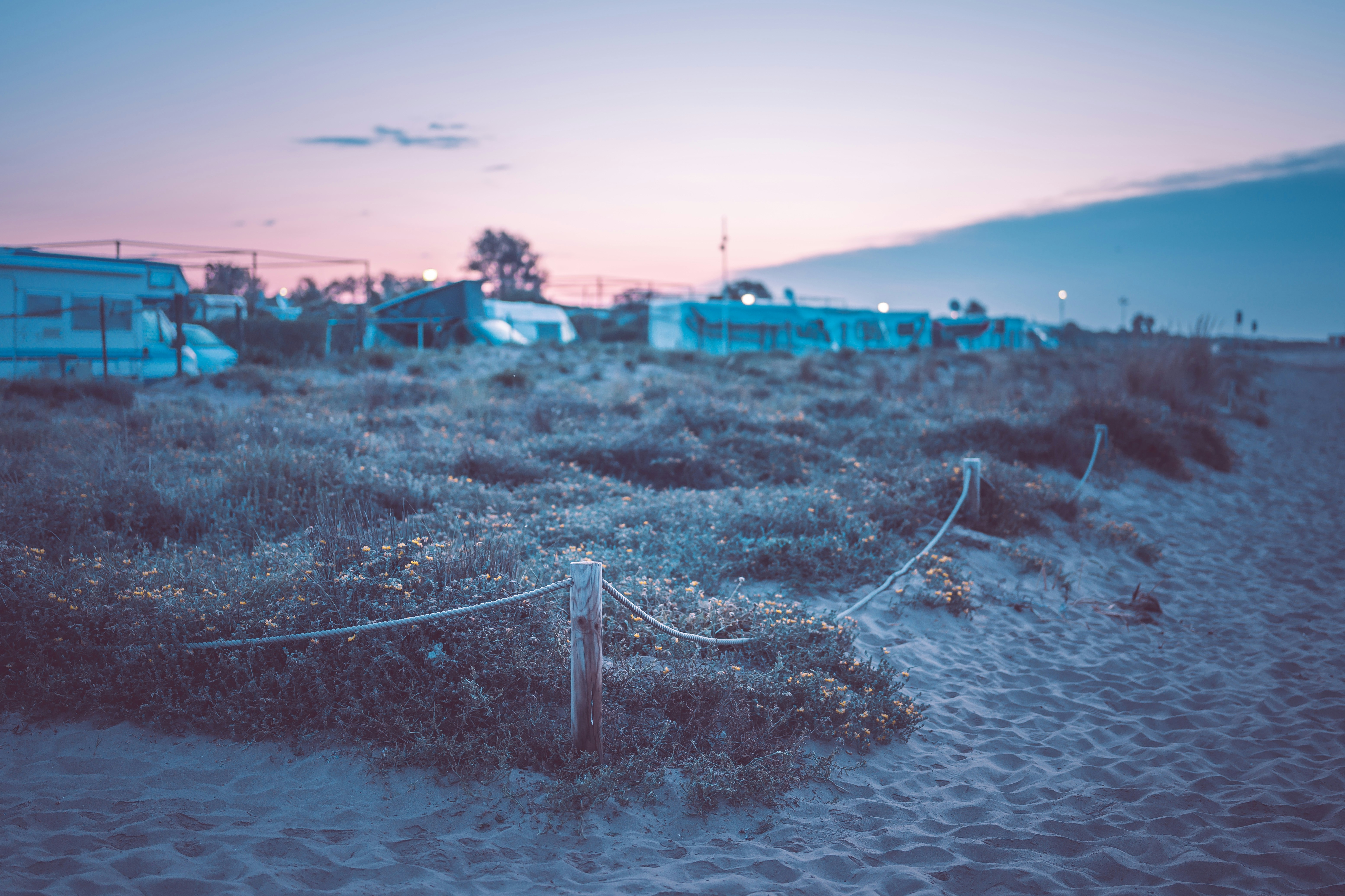 a fence on a beach with a building in the background
