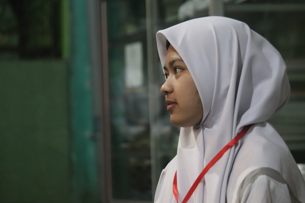 a young woman wearing a white hoodie and a red ribbon around her neck