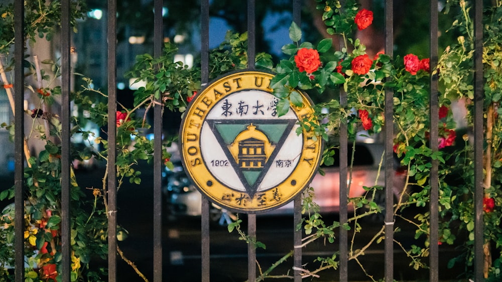 a gate with a sign on it and flowers around it