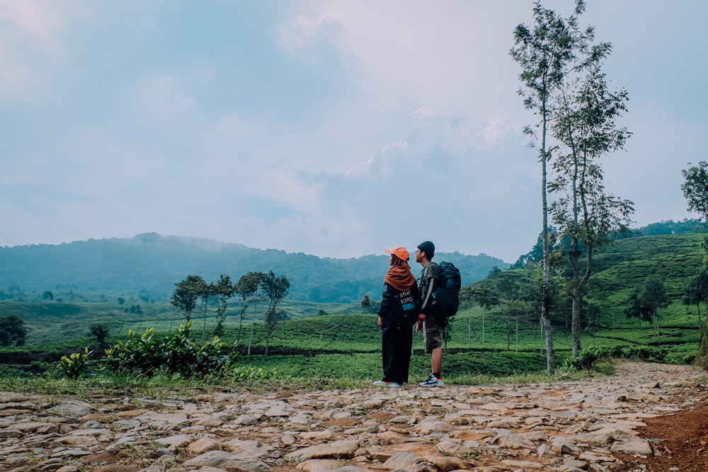 a couple of people standing on top of a dirt road