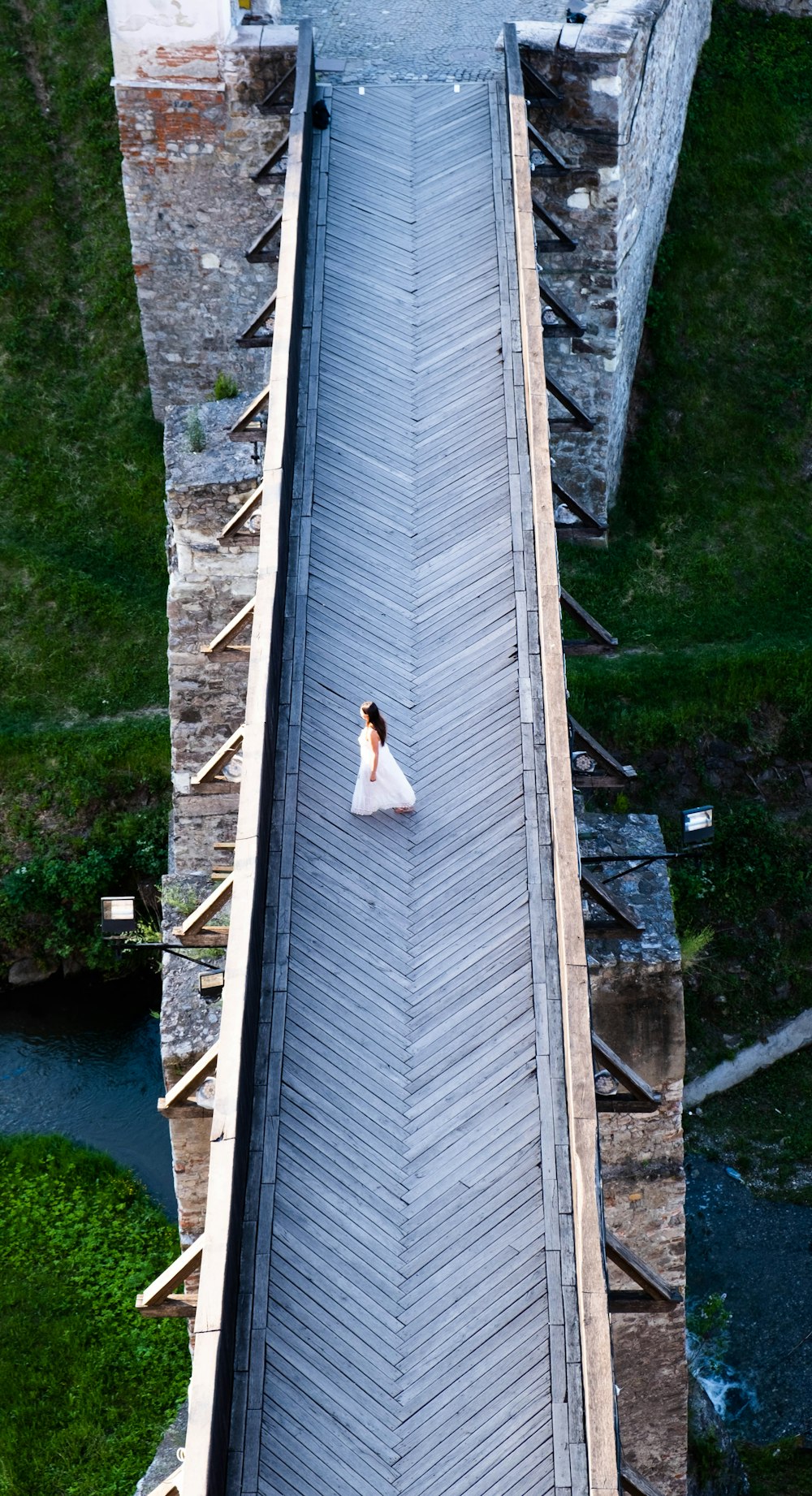 a woman in a white dress standing on a bridge