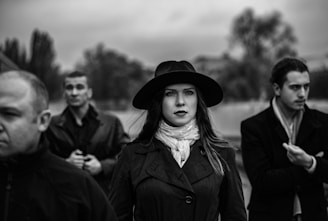 a woman wearing a hat standing in front of a group of men