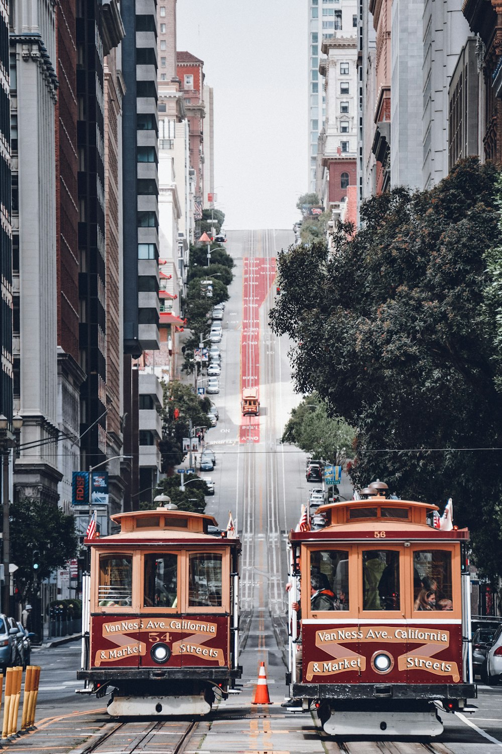 a couple of trolleys driving down a street next to tall buildings