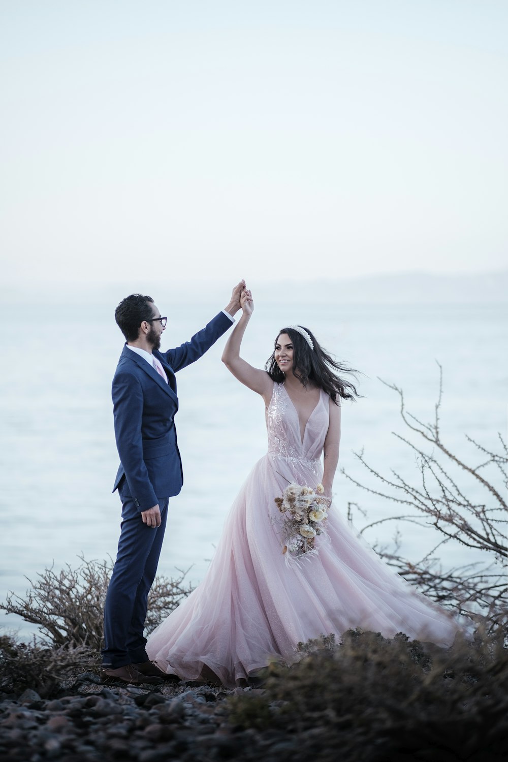 a bride and groom dancing on the beach