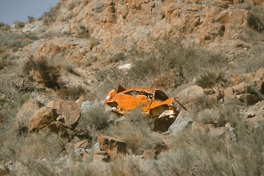 a rusted out car sitting in the middle of a desert