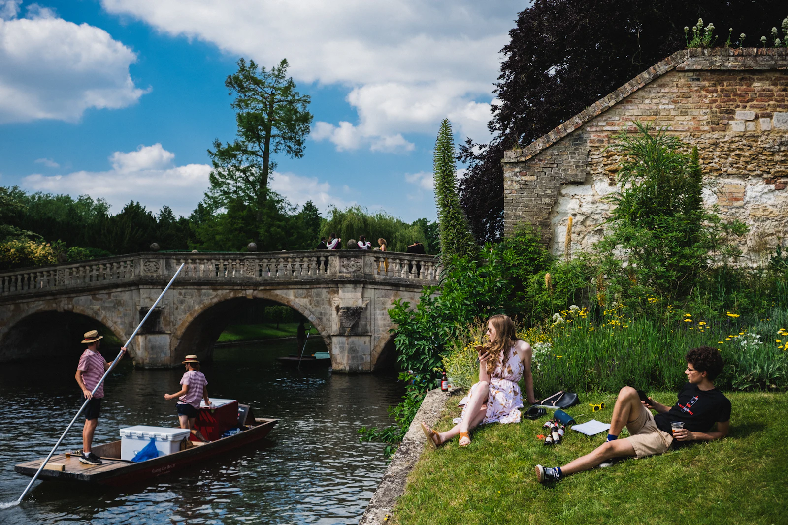 People relaxing on the riverbank by King's College on a summer day
