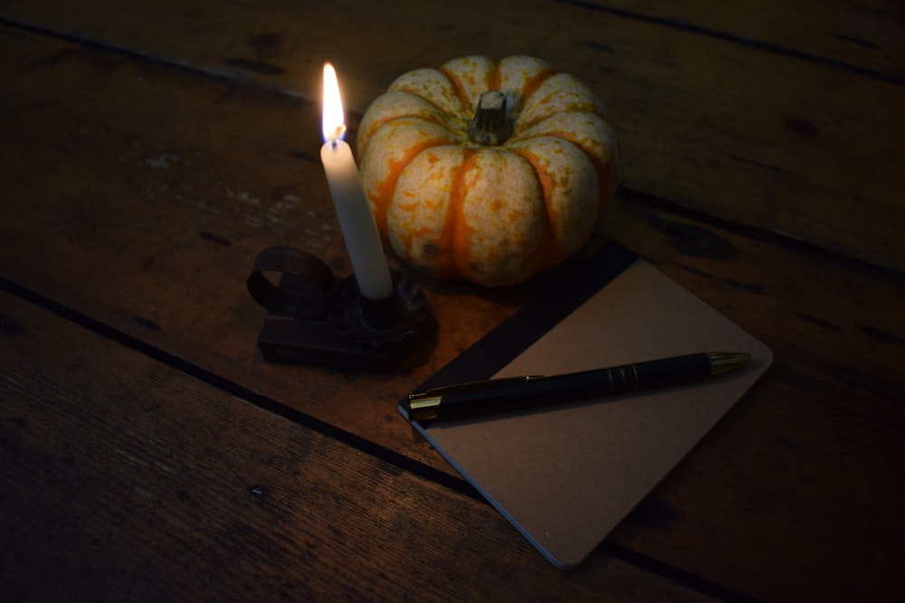 a notepad, pen and a pumpkin on a wooden table