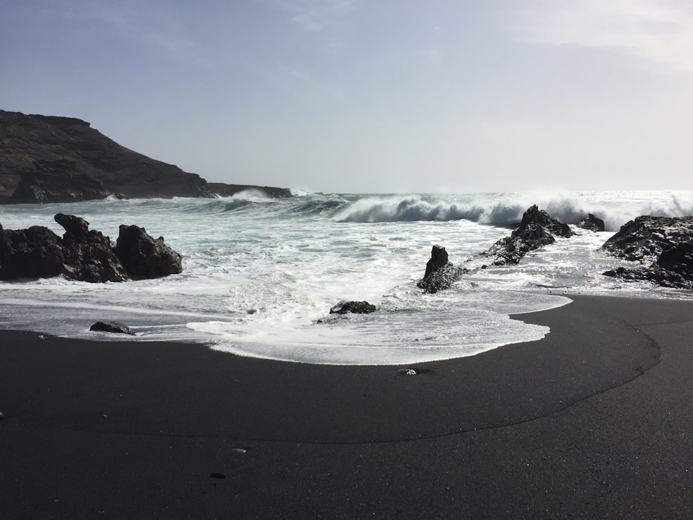 Una playa de arena negra con olas que llegan a la orilla