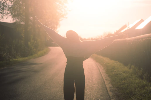 a person standing on a road with their arms outstretched