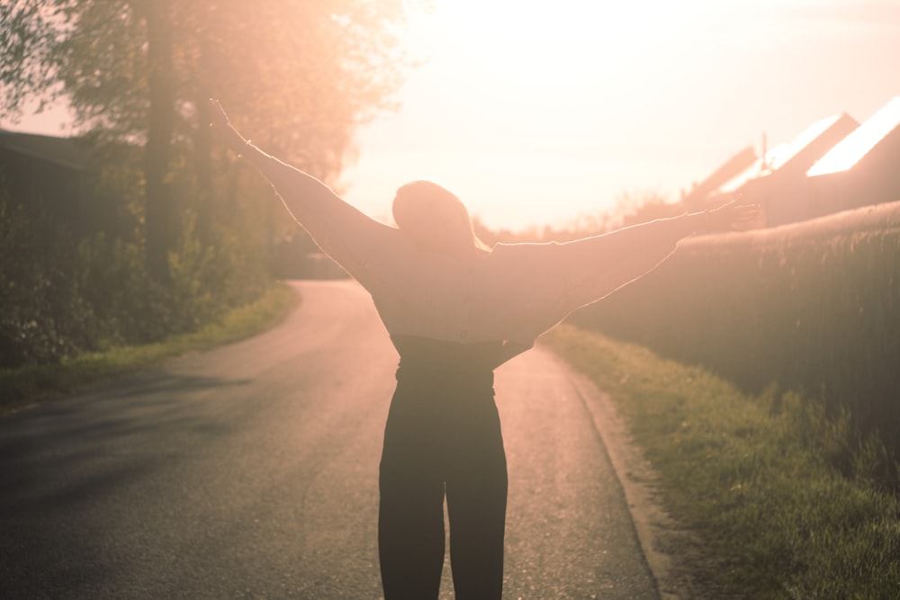 a person standing on a road with their arms outstretched