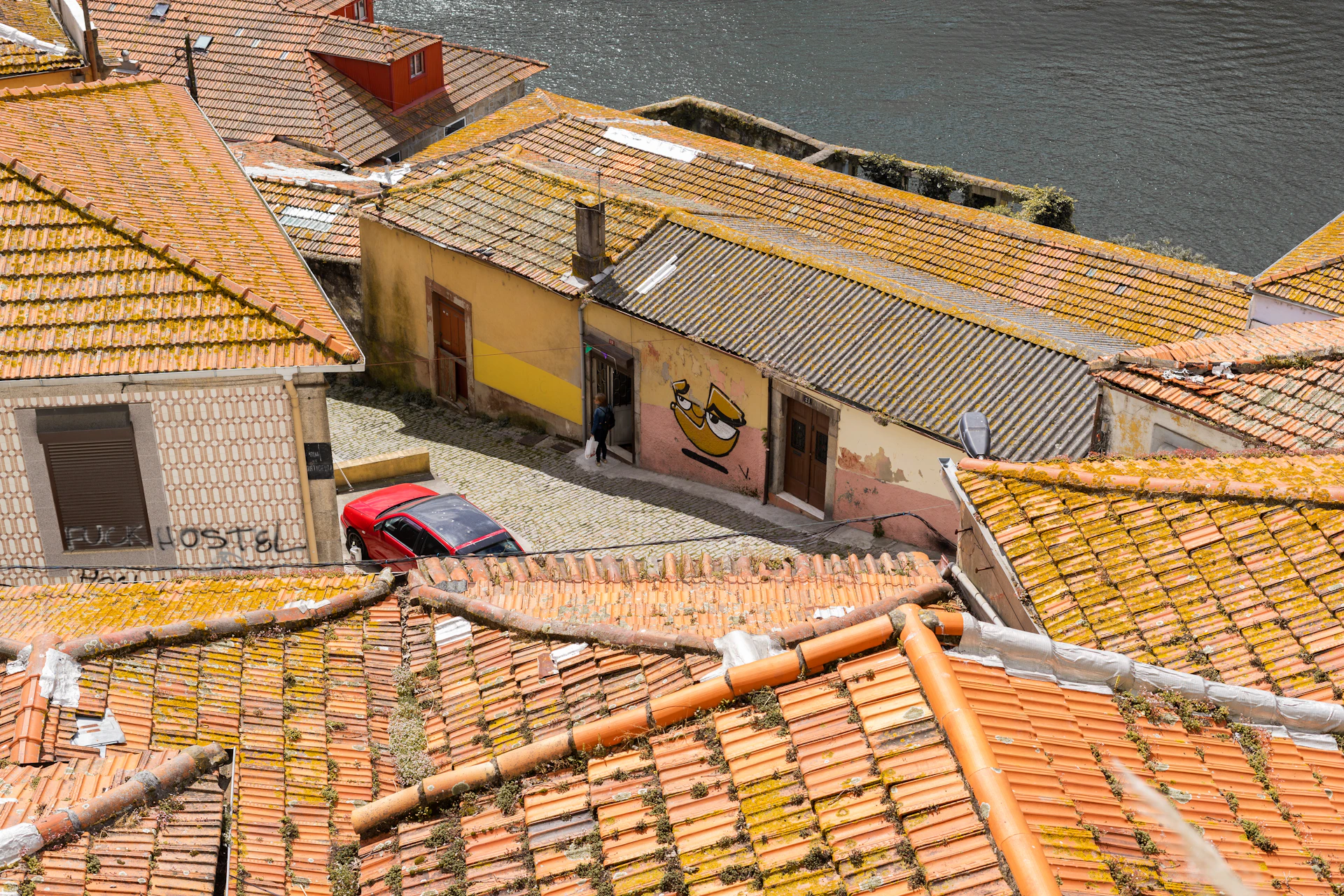 a red car parked on top of a roof next to a body of water