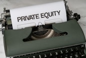 A vintage green typewriter with a sheet of paper inserted displays the text 'PRIVATE EQUITY' in bold letters. The typewriter rests on a white marble surface, and its keys and mechanisms are visible.