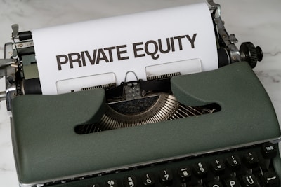 A vintage green typewriter with a sheet of paper inserted displays the text 'PRIVATE EQUITY' in bold letters. The typewriter rests on a white marble surface, and its keys and mechanisms are visible.