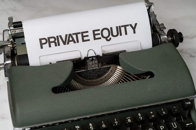 A vintage green typewriter with a sheet of paper inserted displays the text 'PRIVATE EQUITY' in bold letters. The typewriter rests on a white marble surface, and its keys and mechanisms are visible.