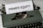 A vintage green typewriter with a sheet of paper inserted displays the text 'PRIVATE EQUITY' in bold letters. The typewriter rests on a white marble surface, and its keys and mechanisms are visible.
