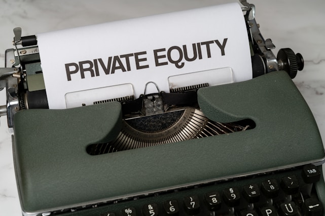 A vintage green typewriter with a sheet of paper inserted displays the text 'PRIVATE EQUITY' in bold letters. The typewriter rests on a white marble surface, and its keys and mechanisms are visible.