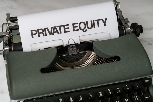 A vintage green typewriter with a sheet of paper inserted displays the text 'PRIVATE EQUITY' in bold letters. The typewriter rests on a white marble surface, and its keys and mechanisms are visible.