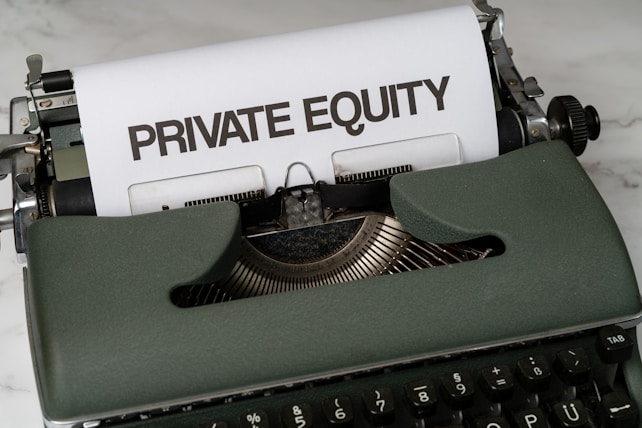 A vintage green typewriter with a sheet of paper inserted displays the text 'PRIVATE EQUITY' in bold letters. The typewriter rests on a white marble surface, and its keys and mechanisms are visible.