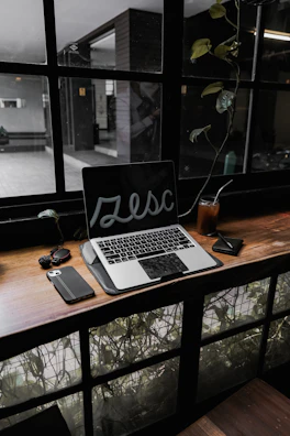 An AI assistant device on a desk next to a notebook and coffee cup in natural light
