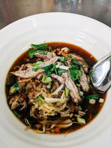 A steaming bowl of traditional Vietnamese noodles, garnished with fresh herbs.
