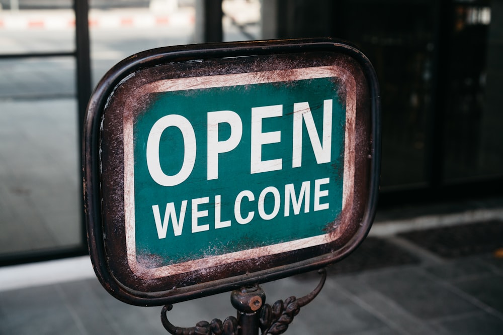 a green and white sign that says open welcome