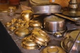 a table topped with lots of brass pots and pans