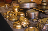 a table topped with lots of brass pots and pans